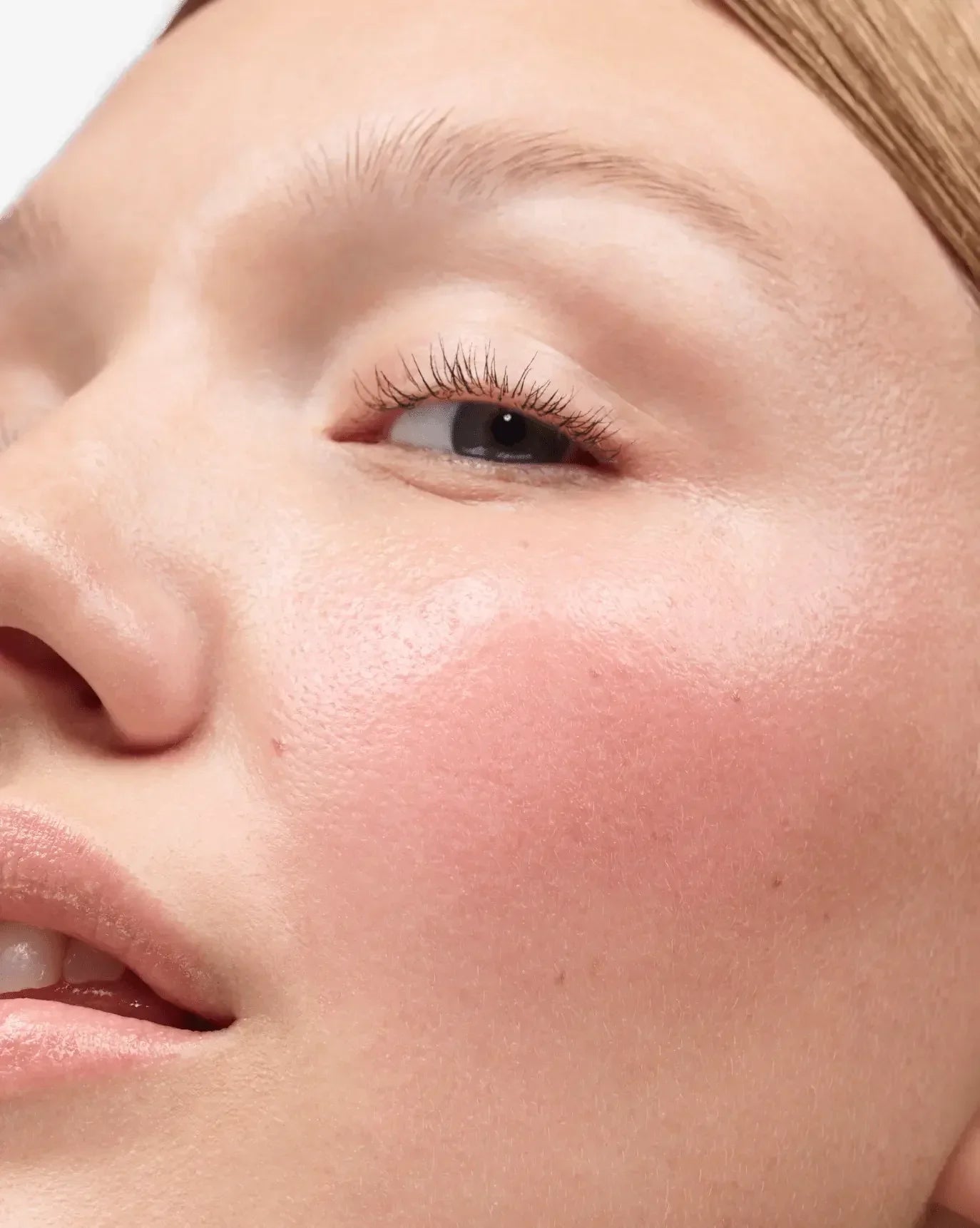 Close-up of dewy, radiant cheek with soft pink blush and creamy texture makeup finish