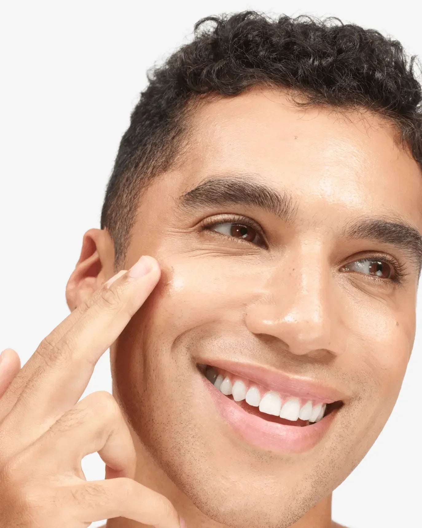 Smiling person applying creamy, dewy blush to cheek for radiant, natural makeup look