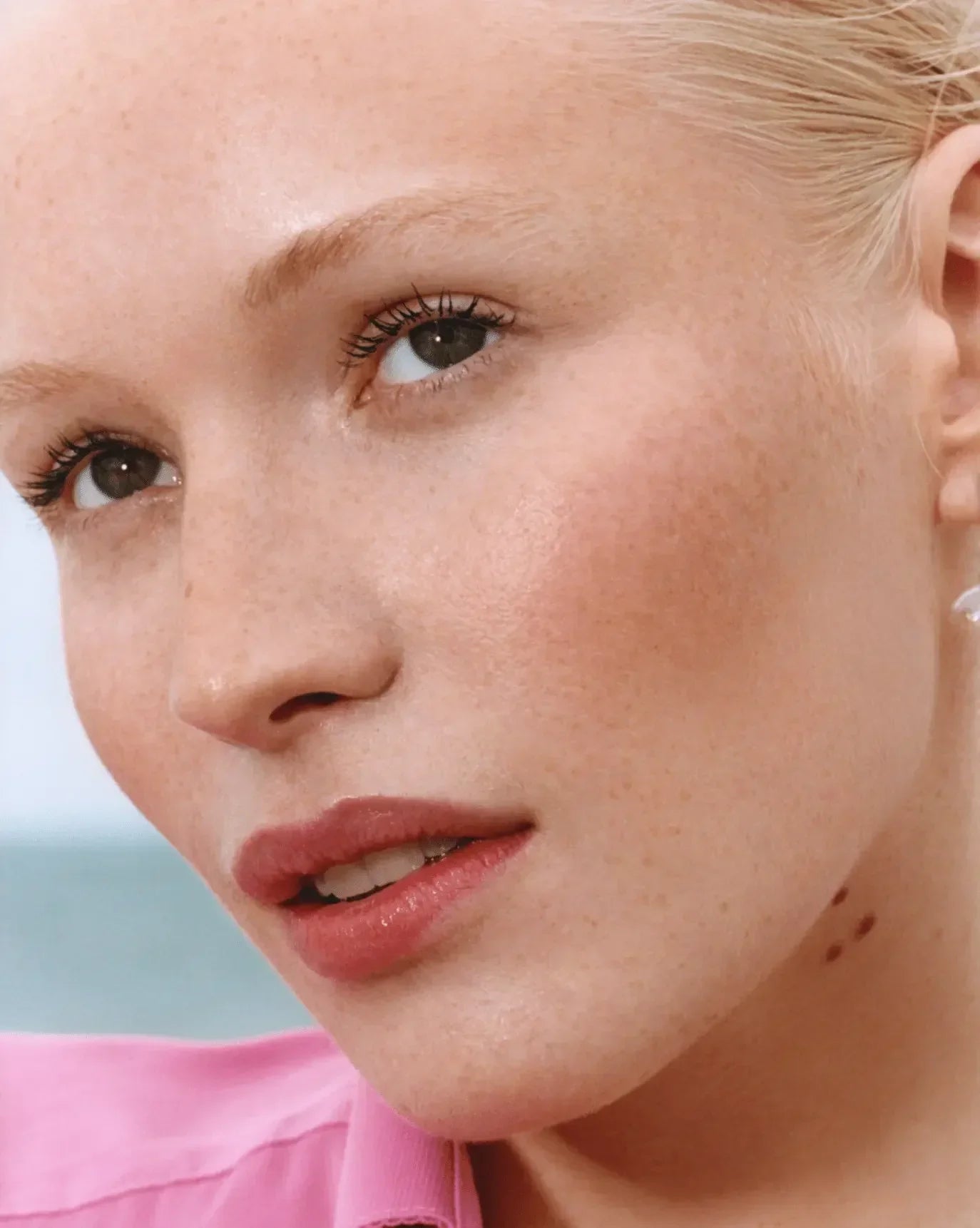 Close-up of a model with dewy skin, natural pink blush, and soft rose lip color