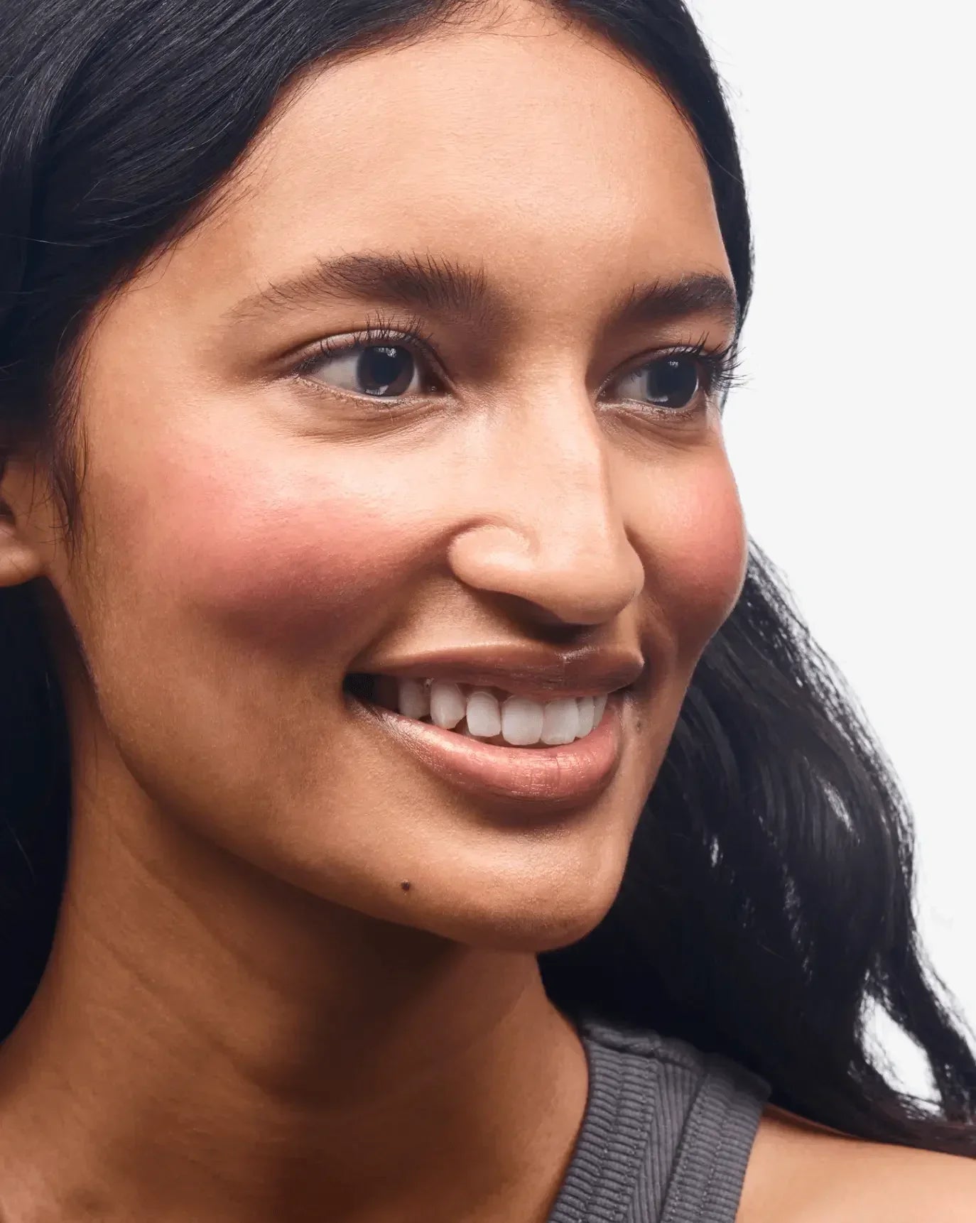 Woman with radiant skin wearing soft, rosy cream blush for a dewy, natural finish.
