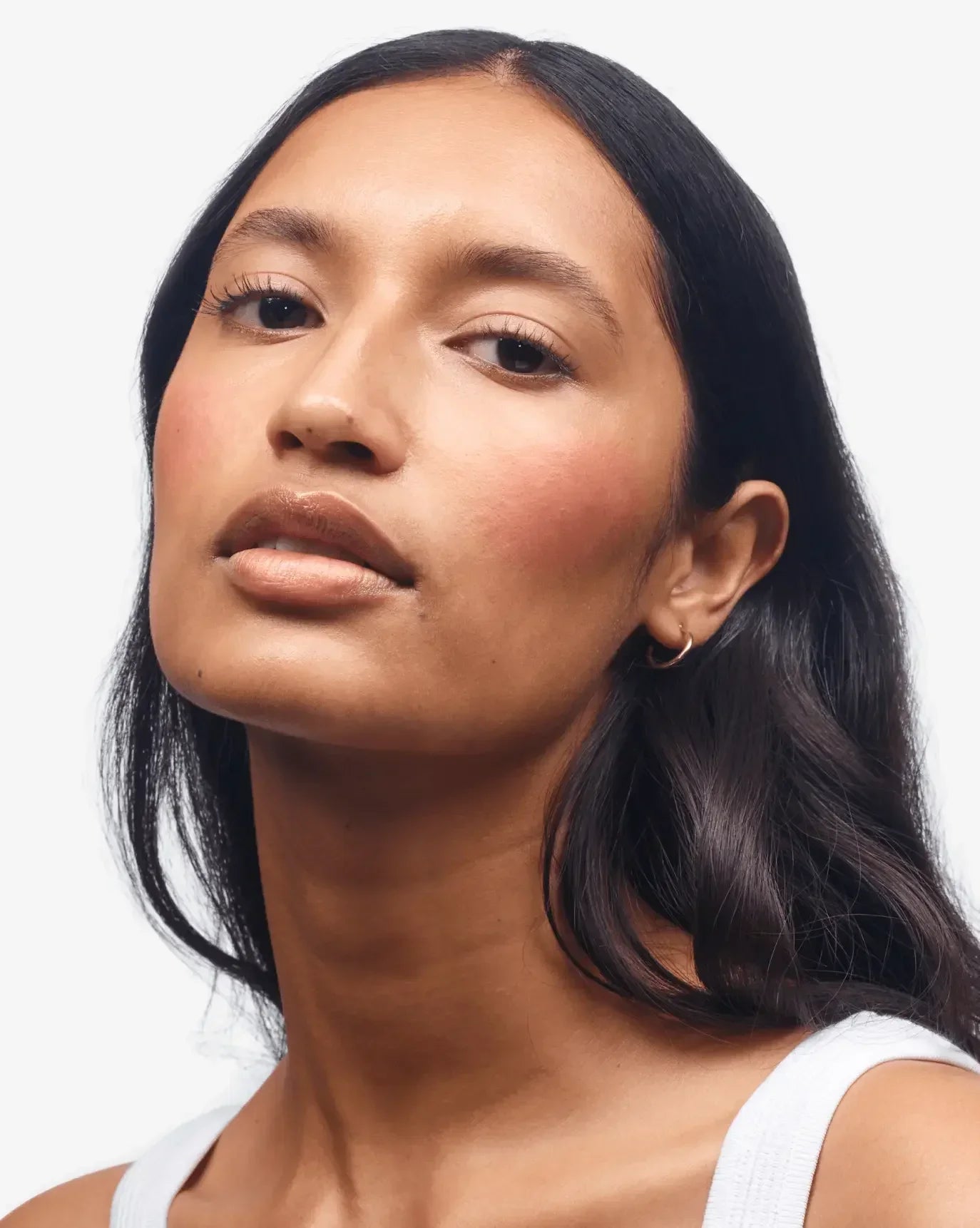 Woman with radiant skin and dewy peach blush, creamy texture, close-up makeup look
