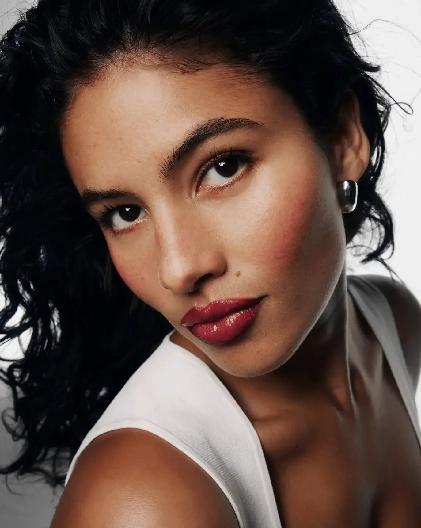 Model with radiant skin, dewy finish blush, and bold berry lip color, close-up