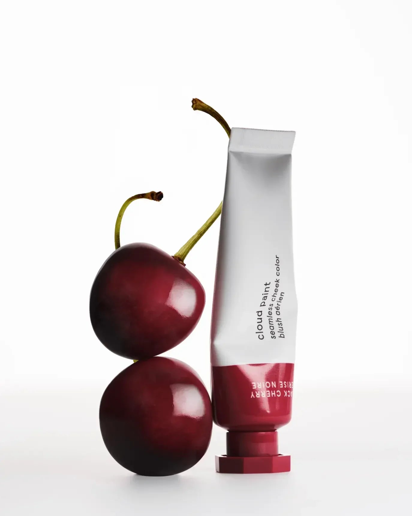 Creamy berry-toned blush tube with rich, glossy cherries on a white background