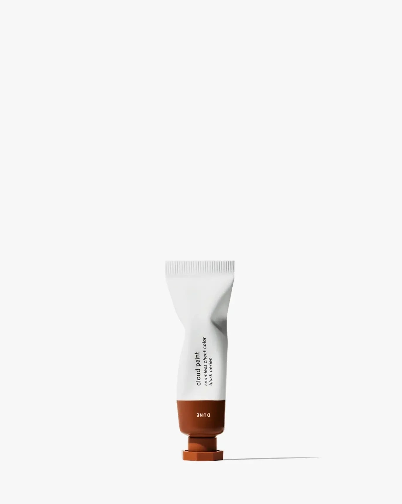 Tube of Cloud Paint blush in warm terracotta shade with creamy, blendable texture on white background