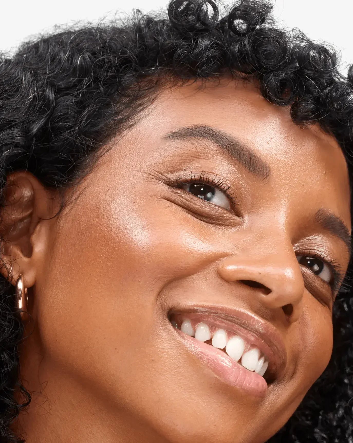 Close-up of a woman with glowing skin, natural blush, and a dewy, radiant finish.