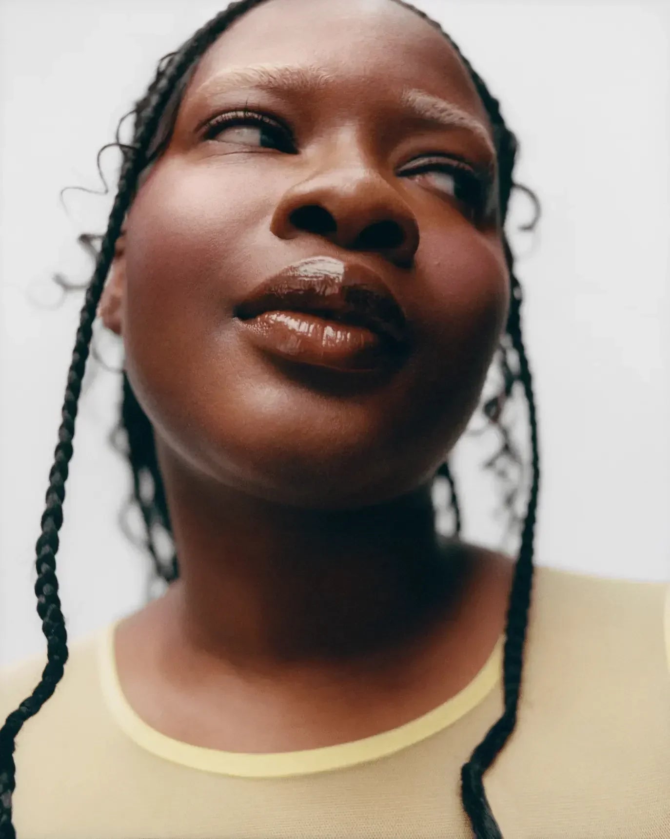 Close-up of a woman with dewy, luminous skin, glossy lips, and subtle rosy blush.