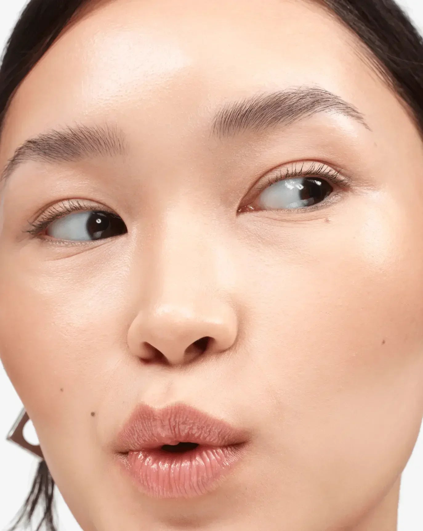 Close-up of dewy, radiant skin with a natural blush and creamy nude lips