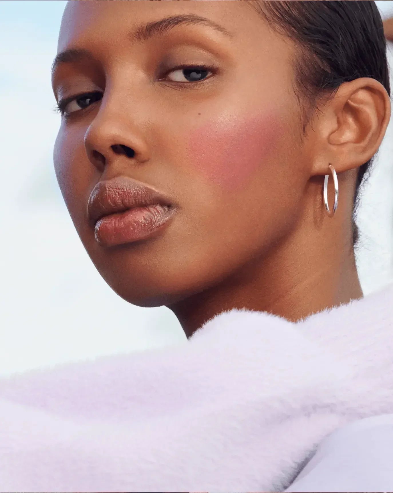 Model with radiant, dewy blush in a soft pink hue, showcasing a natural, luminous finish.