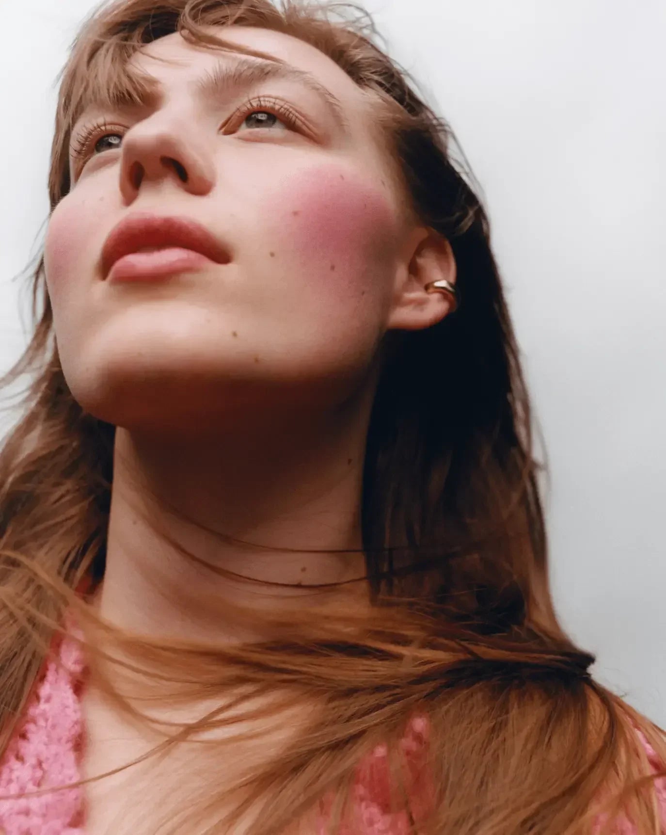 Model with rosy, dewy blush and natural makeup, showcasing soft pink radiant cheeks