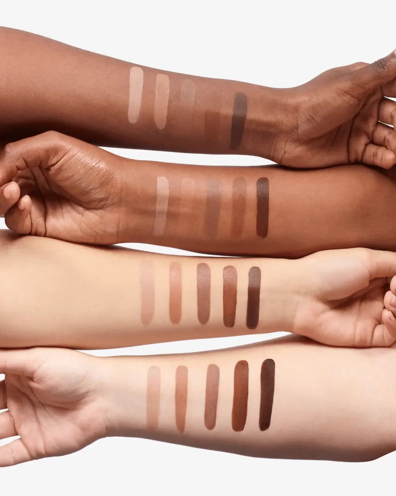 Four arms with diverse skin tones displaying creamy contour makeup swatches in neutral and brown shades.