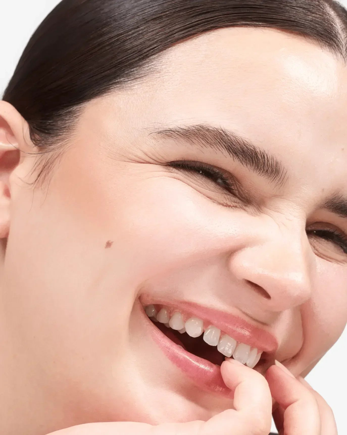 Close-up of radiant skin with soft peach cream blush and a dewy, luminous finish.