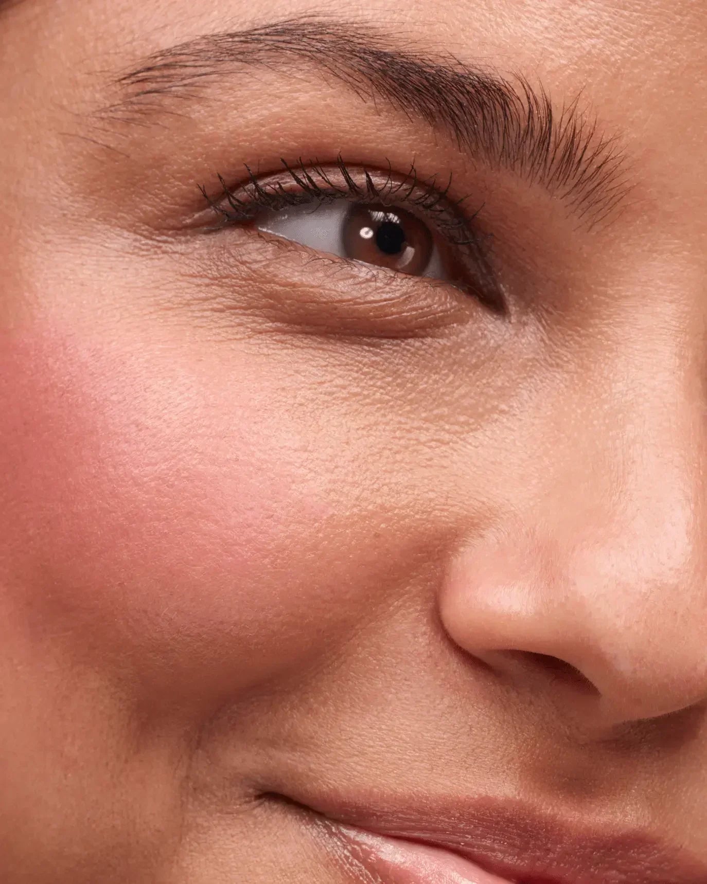 Close-up of cheek with soft rosy blush, dewy finish, and smooth natural skin texture