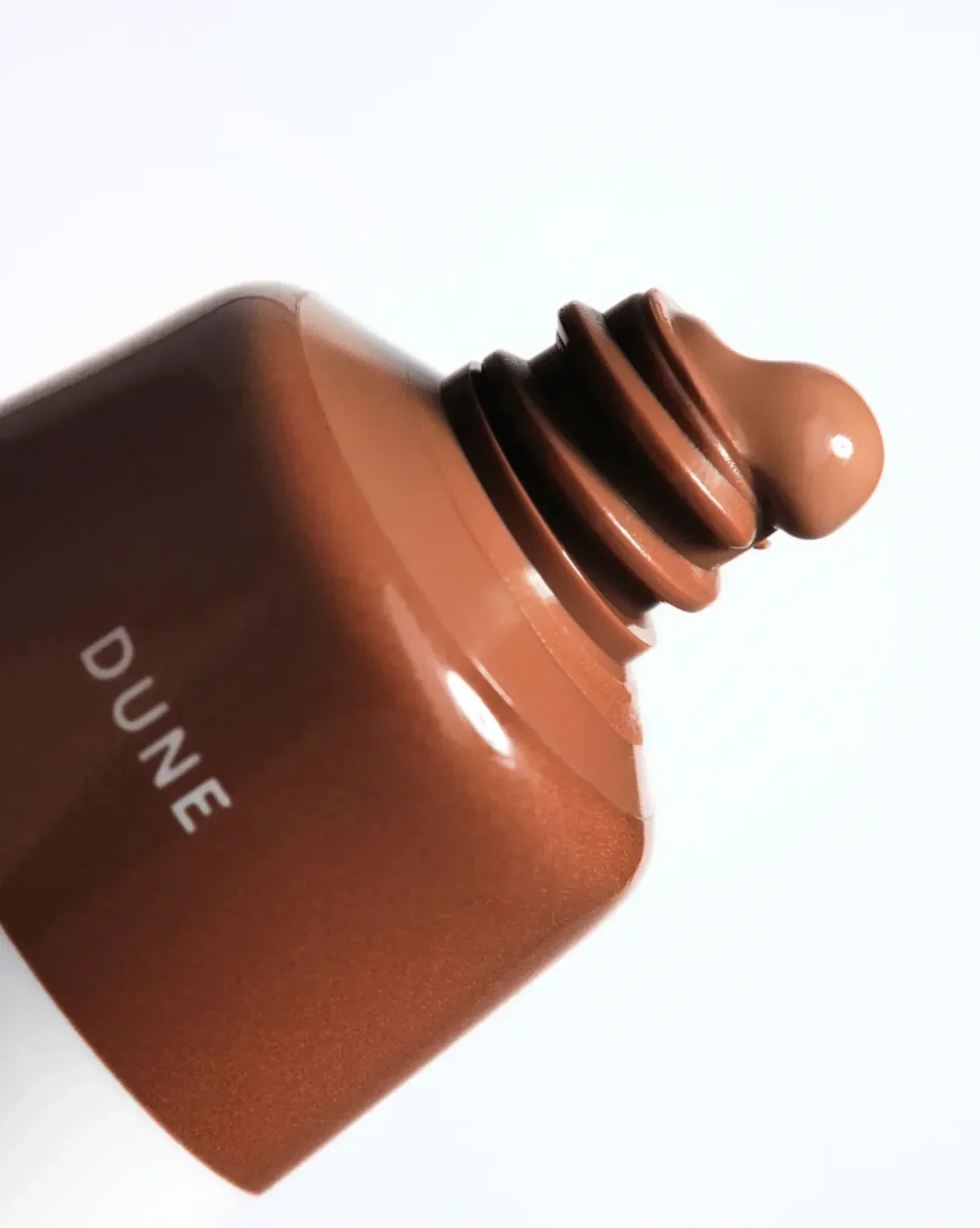 Close-up of creamy liquid blush in warm dune shade with a radiant finish
