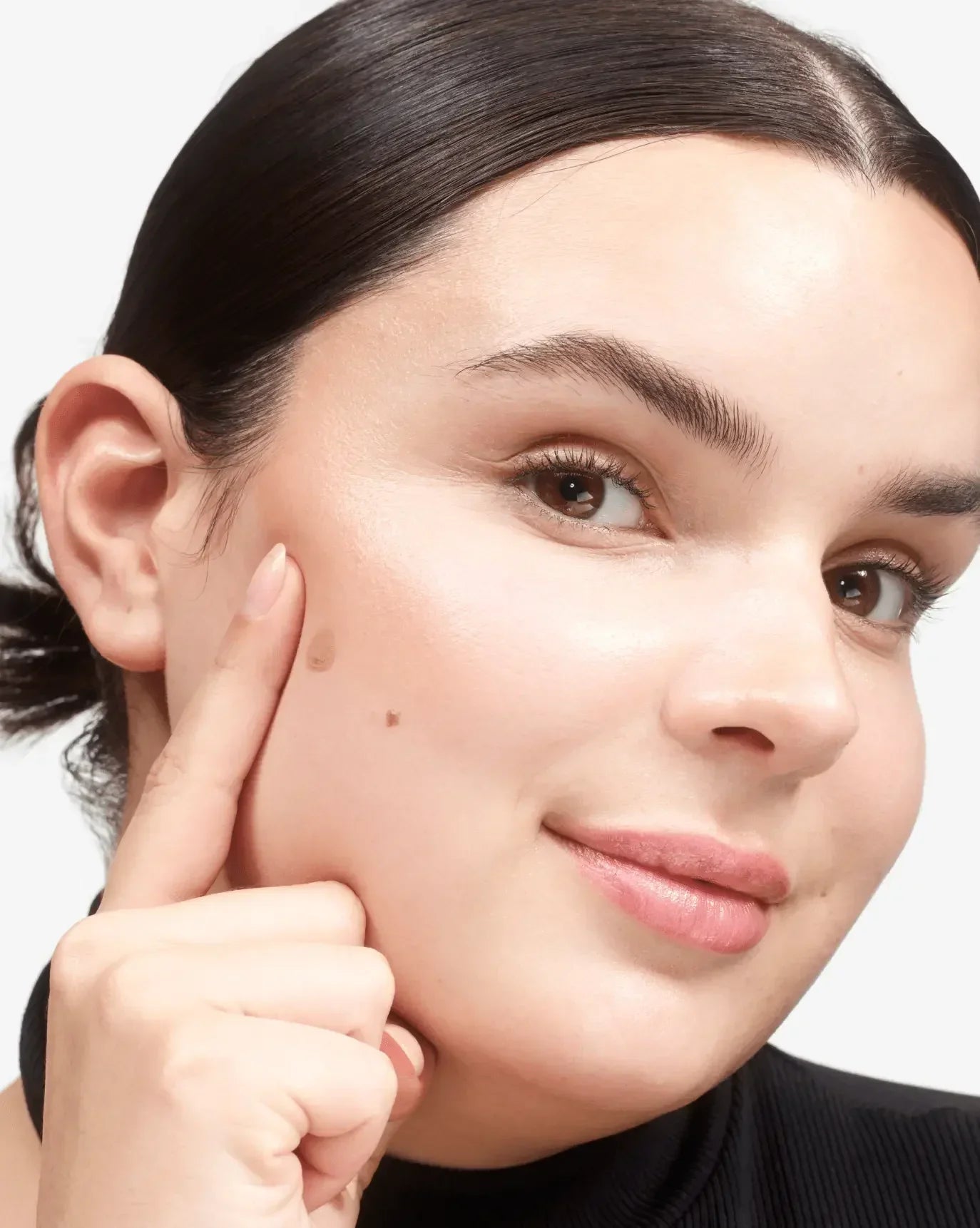 Model with flawless, dewy skin showcases soft peach blush with a luminous, natural finish.