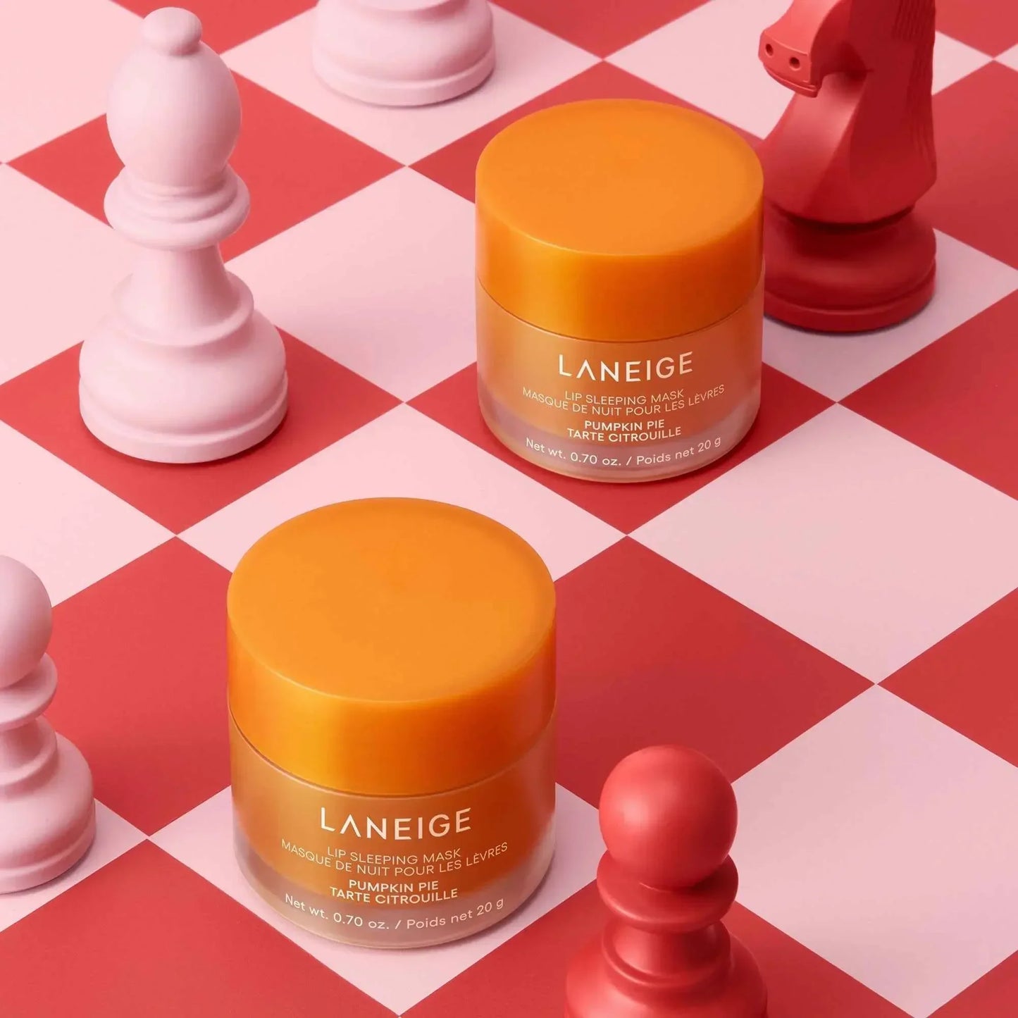 Luxurious orange Laneige lip sleeping mask jars on a red and pink chessboard, creamy texture