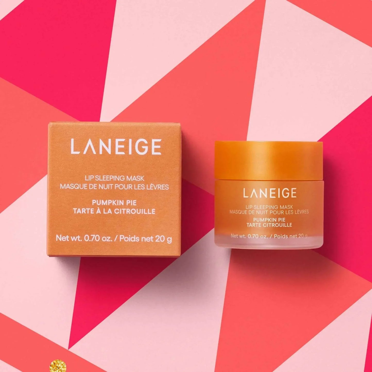 Laneige Pumpkin Pie Lip Sleeping Mask with creamy texture in an orange jar, on geometric pink background.