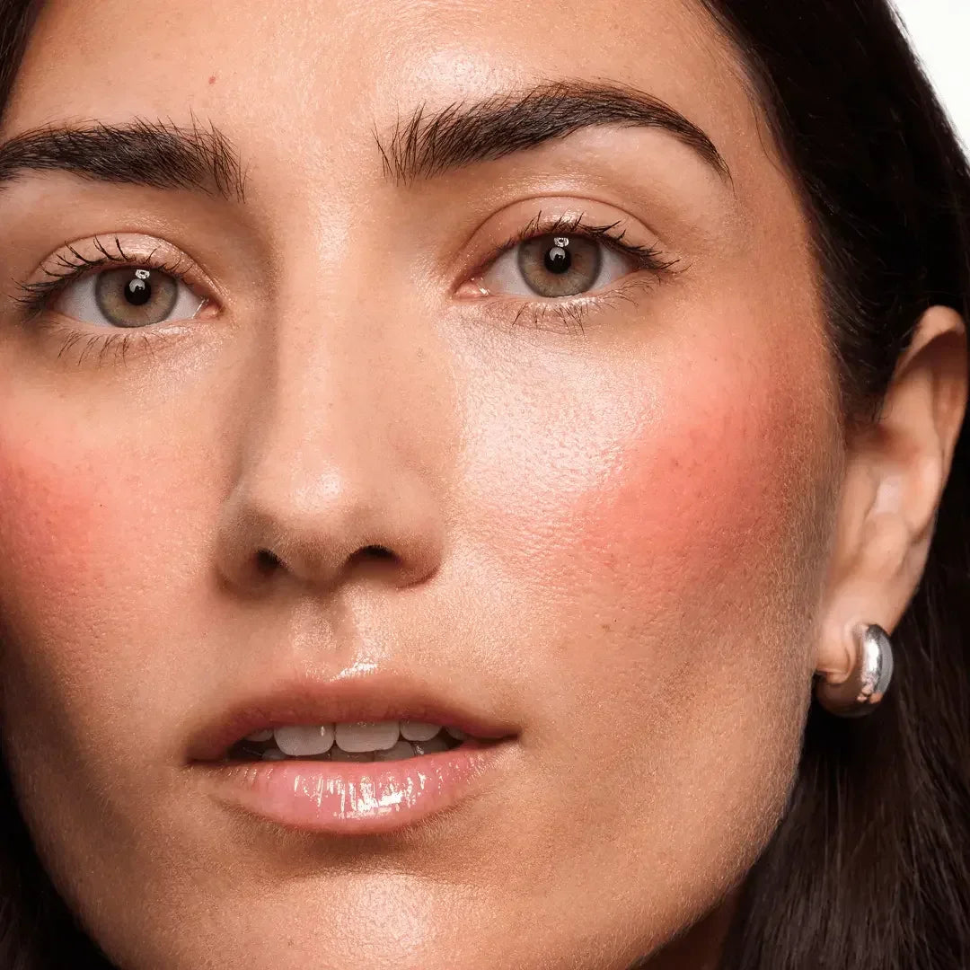 Close-up of woman with radiant dewy blush, soft pink cheeks, and glossy lips