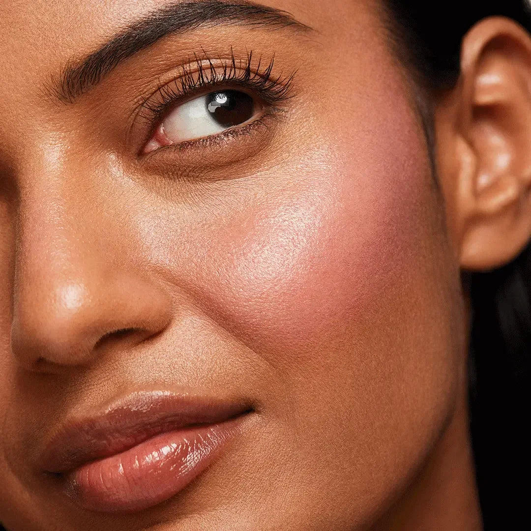 Close-up of a woman's cheek with rosy pink dewy blush and radiant skin texture
