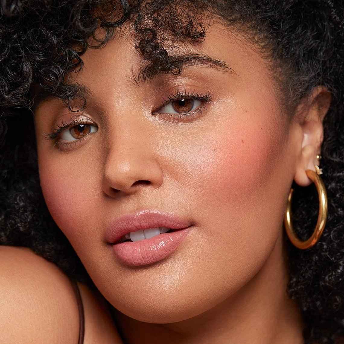 Close-up of model with radiant, dewy blush, soft pink lips, and luminous skin texture.