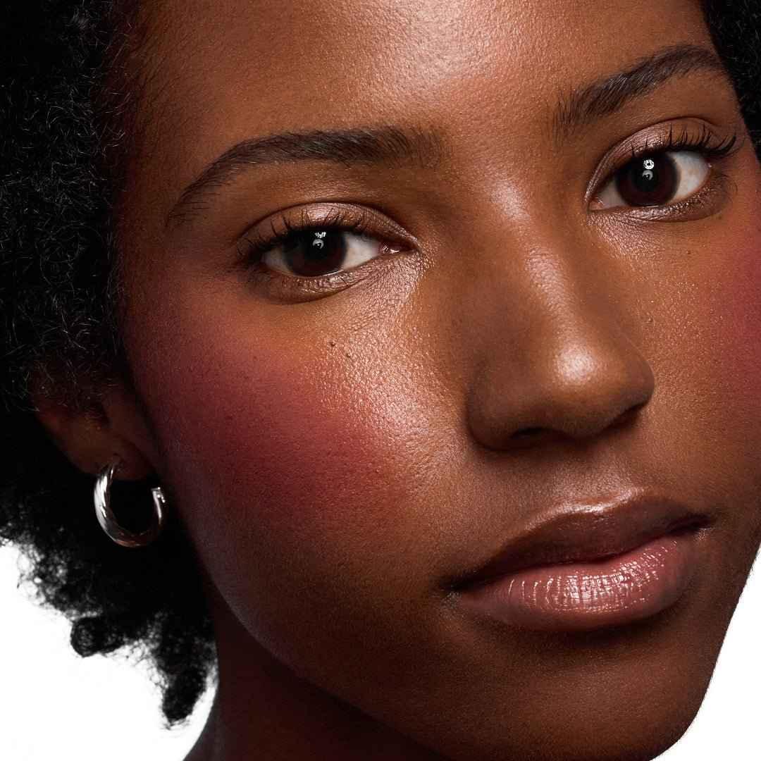 Close-up of model with radiant skin, dewy blush and creamy pink cheek color, natural makeup look.