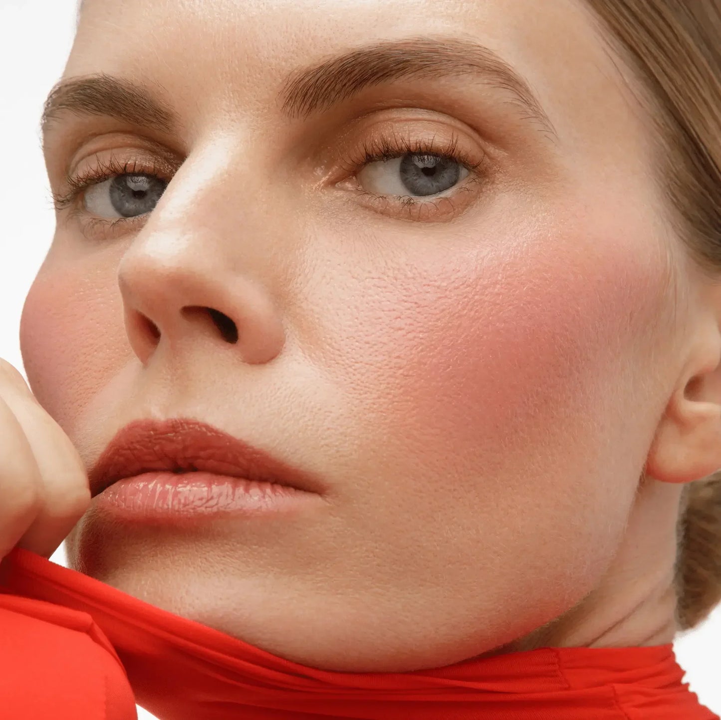 Close-up of model with dewy blush, soft pink cheeks, natural makeup, and creamy texture.