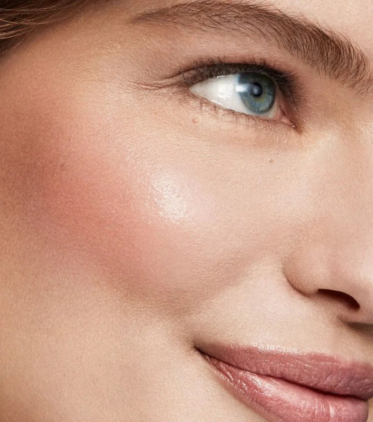 Closeup of glowing skin with rosy blush and dewy finish, showcasing luxury beauty makeup