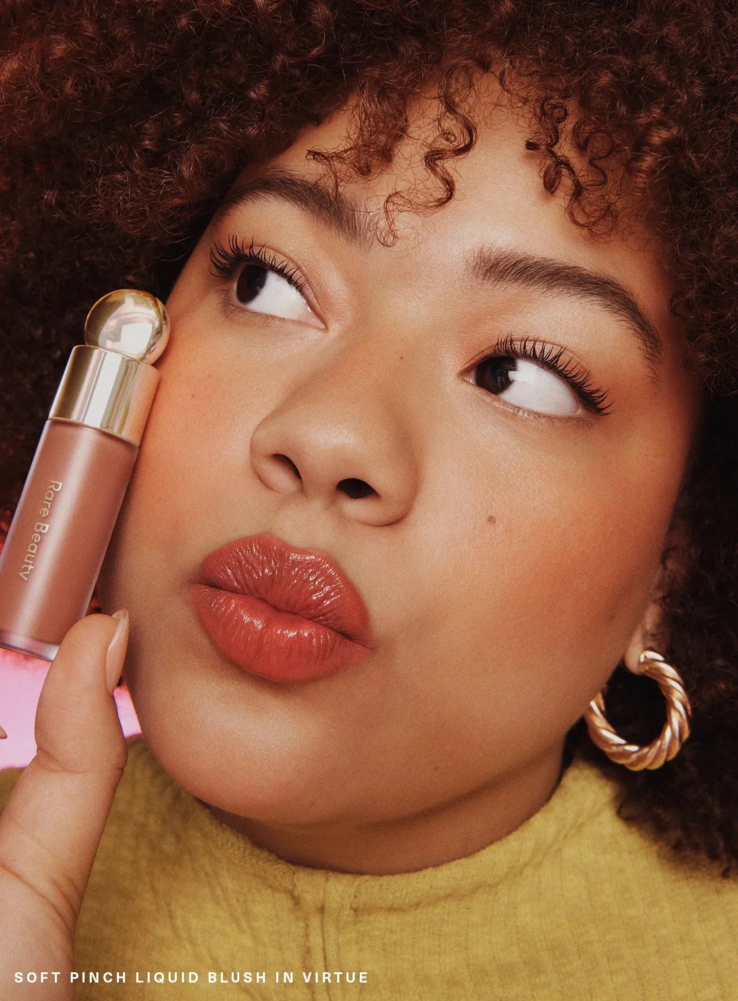 Virtue| A model wearing Rare Beauty's Soft Pinch Liquid Blush in the dewy beige peach shade "Virtue."