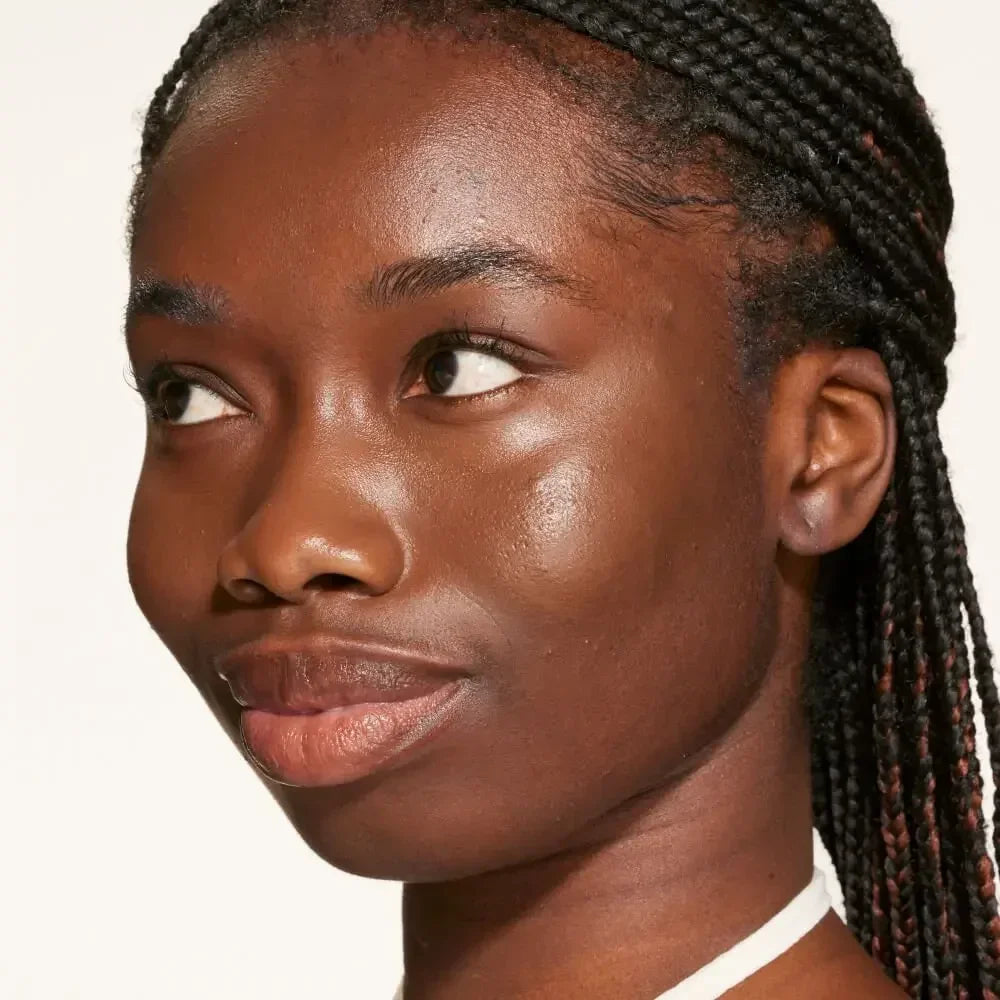 Woman with radiant, dewy skin and braided hair, showcasing luminous complexion.