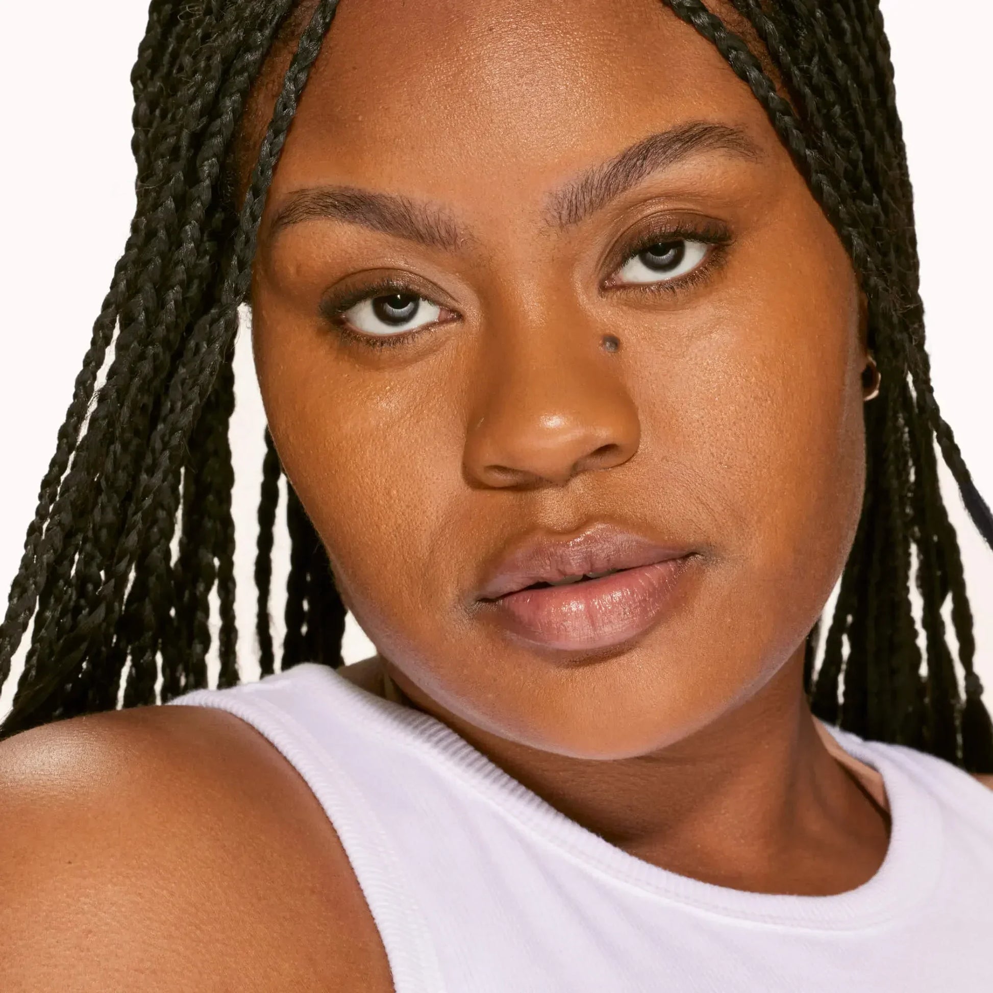 Woman with flawless, radiant skin and a dewy finish, wearing natural makeup and white top