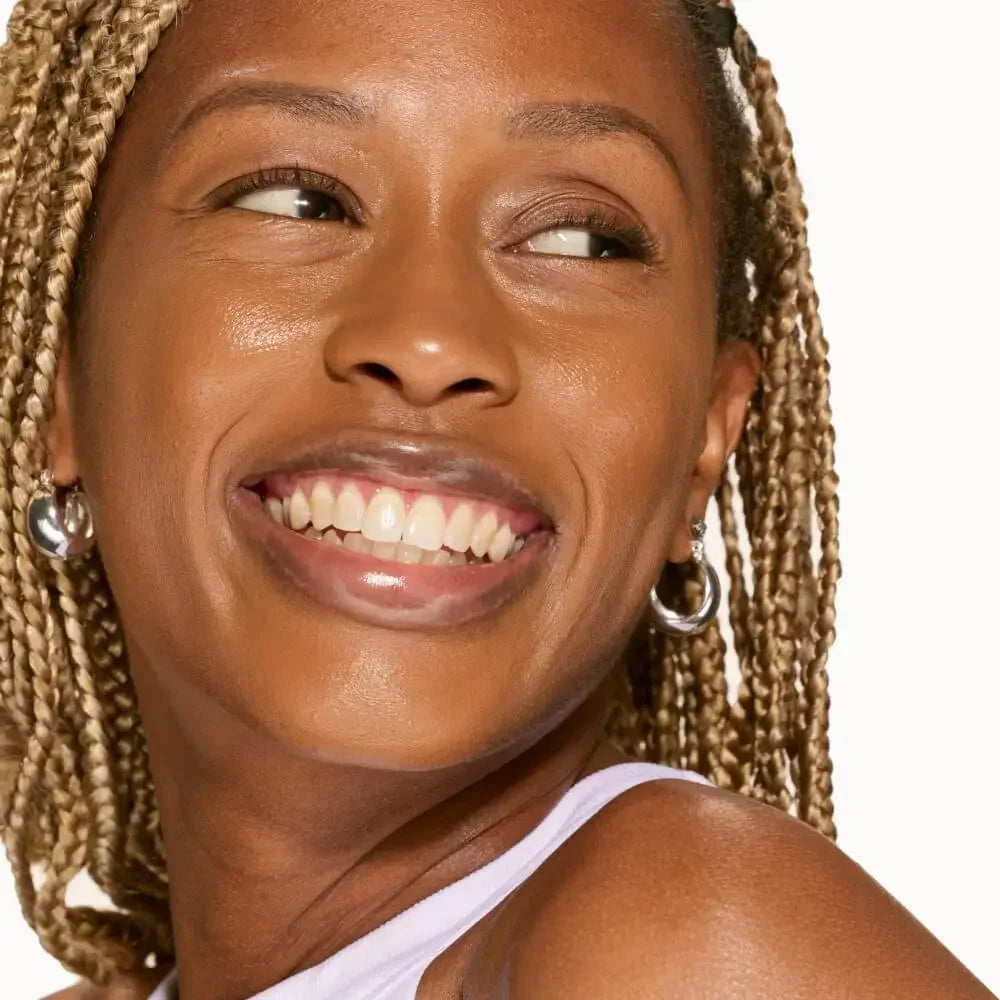 Woman with glowing, dewy complexion and creamy, radiant makeup, smiling in close-up.