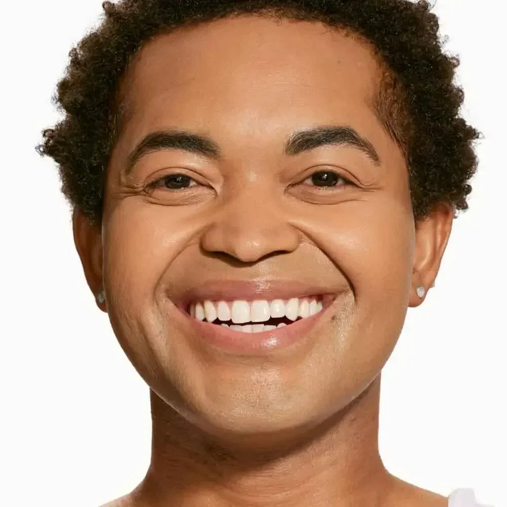 Smiling person with radiant, even skin and dewy finish, showcasing creamy concealer coverage.