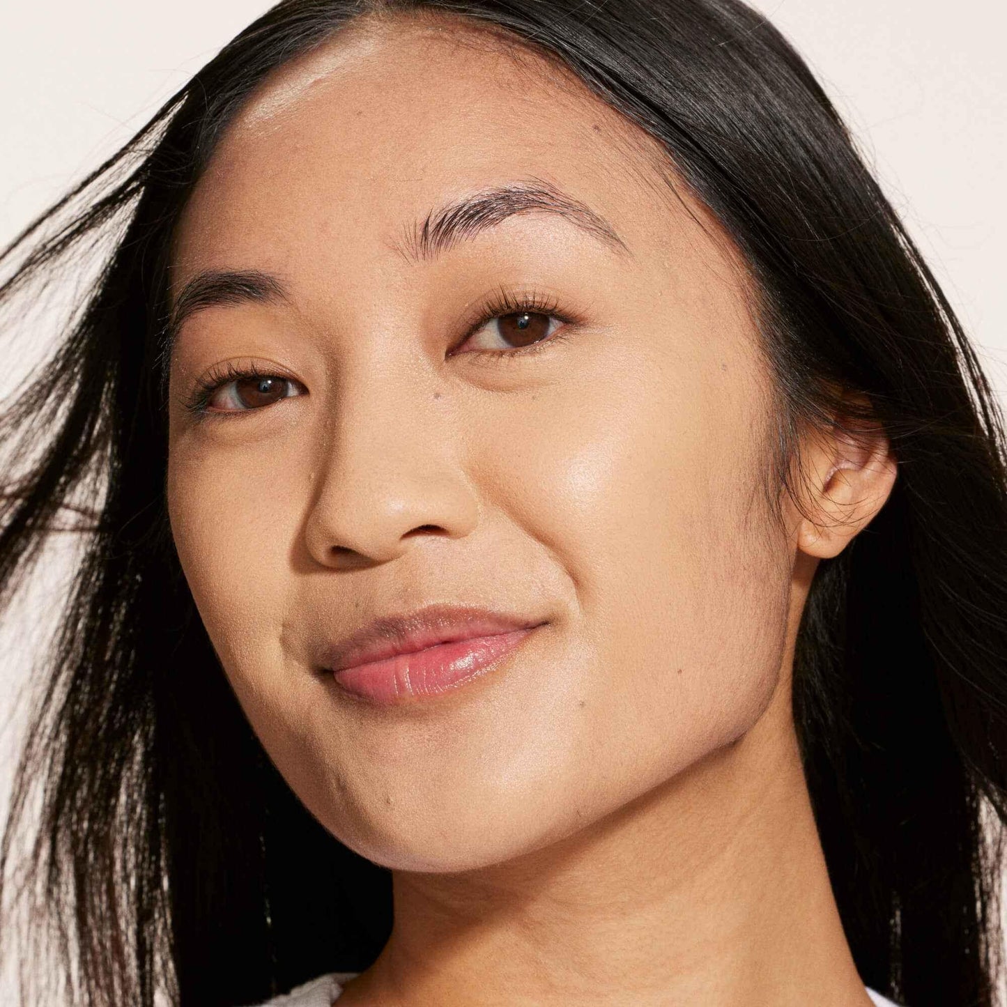 Close-up of woman with flawless skin, subtle makeup, and dewy, radiant finish